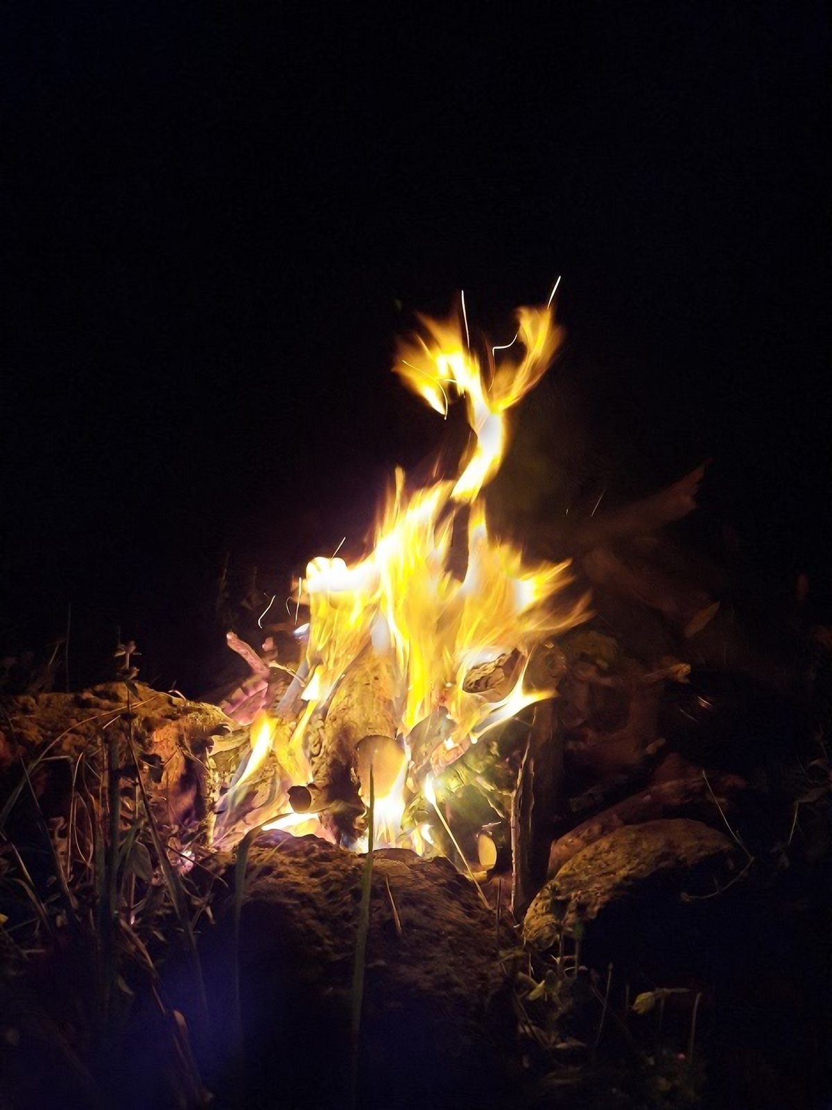 Ein Feuer brennt in der Nacht zwischen Steinen